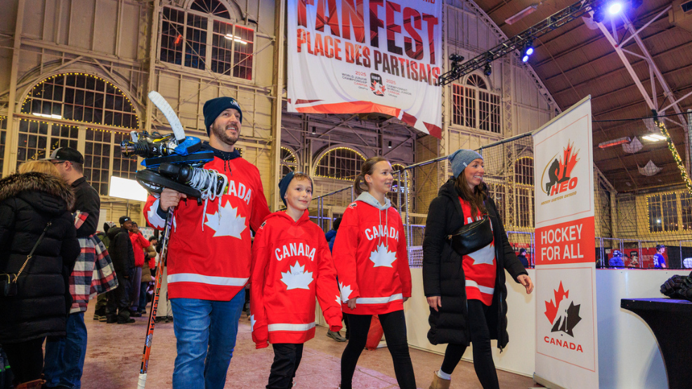 FanFest at IIHF World Juniors 2025, man with hockey stick, two children and a woman walk in Canada jerseys